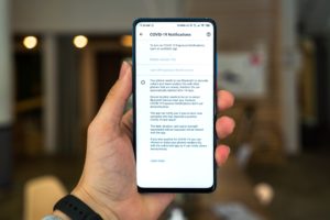 Hand holding a smart phone showing Covid-19 notifications