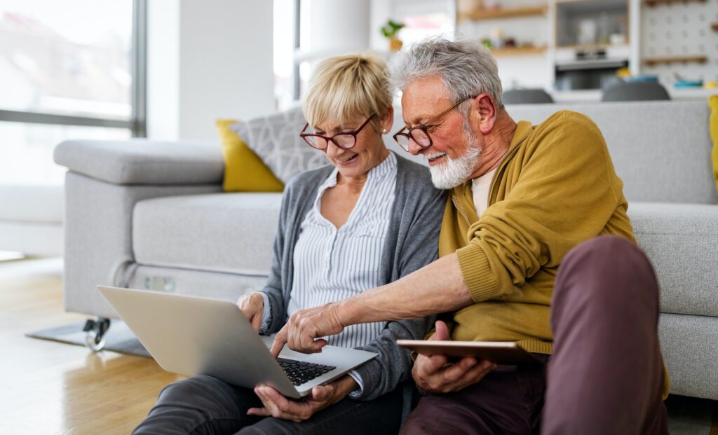 Cheerful senior couple using technology devices and having fun at home